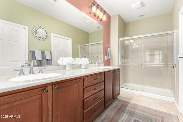 bathroom with tile patterned flooring, double vanity, a stall shower, and a sink