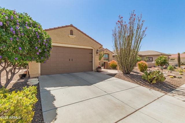 view of front of house featuring stucco siding, a tiled roof, and a garage