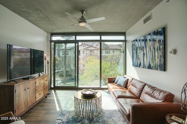 living room featuring a ceiling fan, expansive windows, visible vents, and wood finished floors