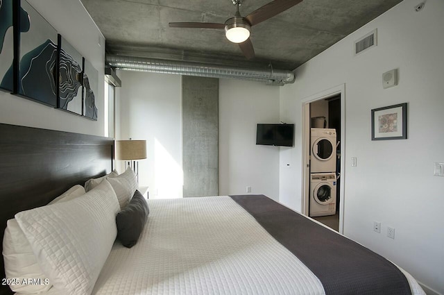 bedroom featuring ceiling fan, visible vents, and stacked washer / drying machine