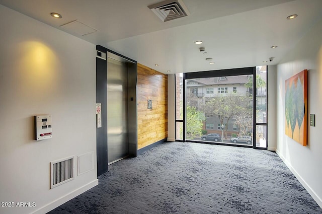 unfurnished room with carpet floors, elevator, visible vents, and floor to ceiling windows