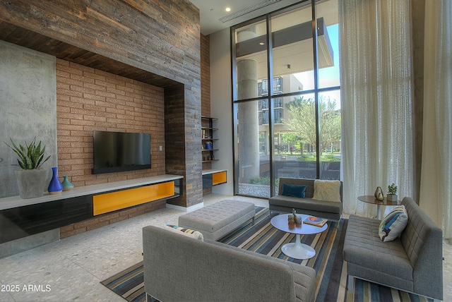 living area featuring a high ceiling, a fireplace, visible vents, and floor to ceiling windows