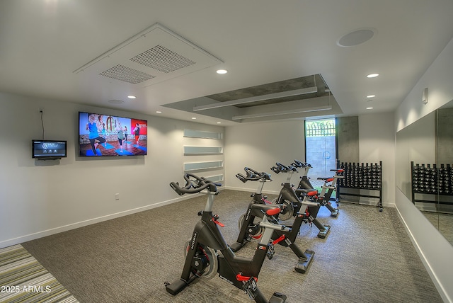 exercise area with visible vents, baseboards, a raised ceiling, and recessed lighting