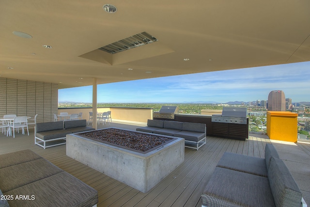 wooden terrace featuring a grill, a view of city, and an outdoor living space with a fire pit