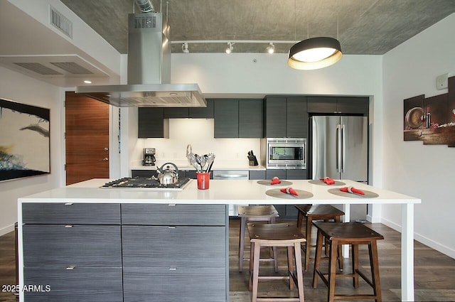 kitchen featuring island range hood, a breakfast bar, light countertops, appliances with stainless steel finishes, and dark wood finished floors