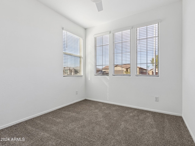 unfurnished room with ceiling fan and dark colored carpet