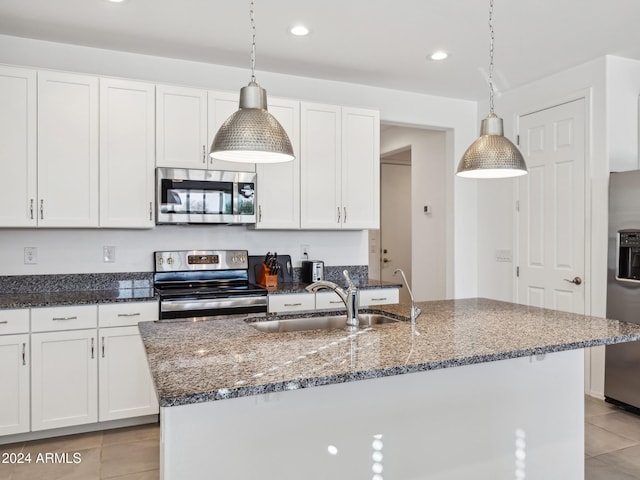 kitchen with white cabinetry, sink, appliances with stainless steel finishes, decorative light fixtures, and an island with sink