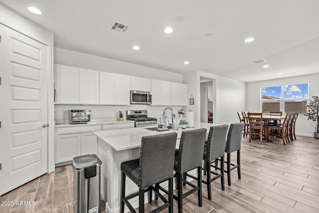 37954 N Greasewood Way, San Tan Valley, AZ 85140 - kitchen with stainless steel appliances, a sink, light wood-type flooring, a breakfast bar area, and light countertops