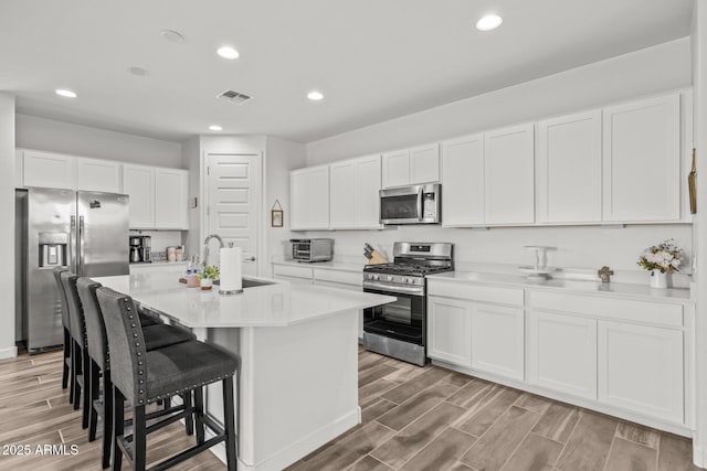 37954 N Greasewood Way, San Tan Valley, AZ 85140 - kitchen featuring appliances with stainless steel finishes, a sink, wood finish floors, a breakfast bar, and recessed lighting