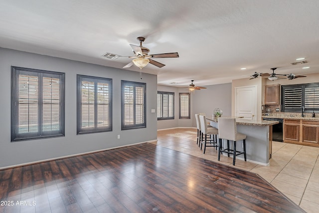 kitchen with a kitchen bar, backsplash, light stone counters, dishwasher, and a kitchen island