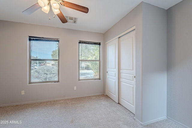 unfurnished bedroom featuring light carpet, a closet, and ceiling fan