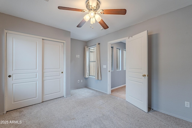 unfurnished bedroom with ceiling fan, light colored carpet, and a closet