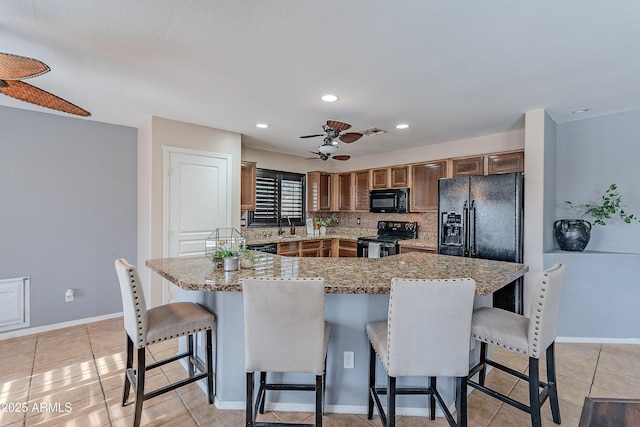 kitchen featuring black appliances, a breakfast bar, light tile patterned flooring, and a kitchen island