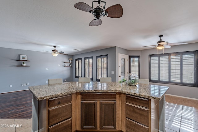 kitchen featuring light stone countertops, a kitchen island, and light tile patterned floors