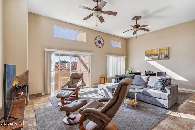 living room featuring ceiling fan, a towering ceiling, and a high end fireplace