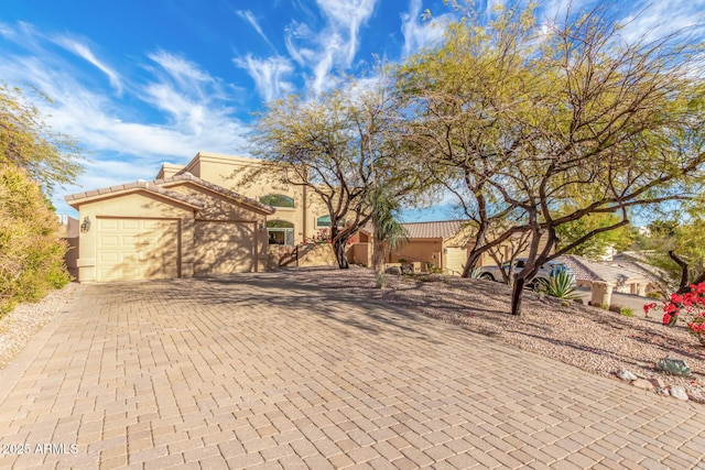 view of front of home featuring a garage, decorative driveway, a tile roof, and stucco siding