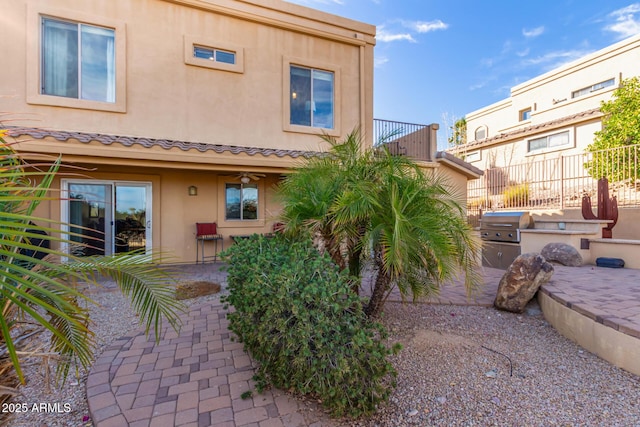 back of property with a patio area, a tiled roof, area for grilling, and stucco siding