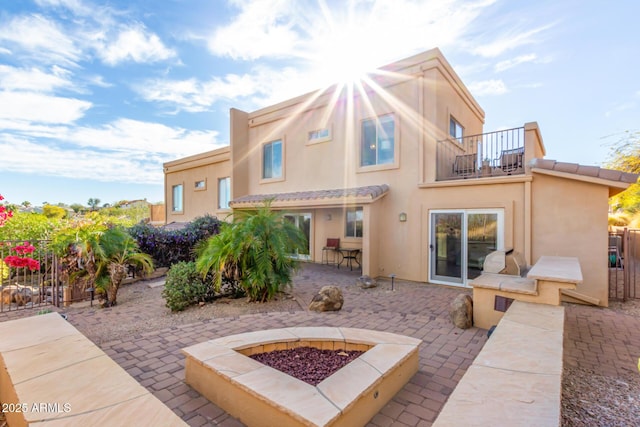 back of house with a patio, stucco siding, fence, a balcony, and a fire pit