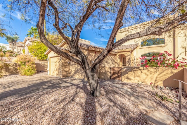 mediterranean / spanish house with an attached garage, driveway, a tiled roof, and stucco siding