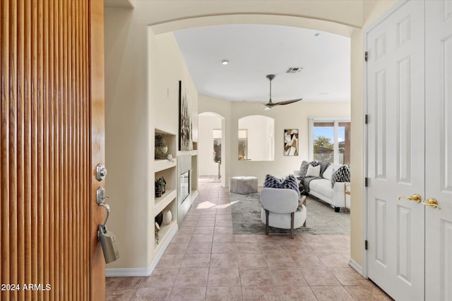 tiled living room with ceiling fan and built in features