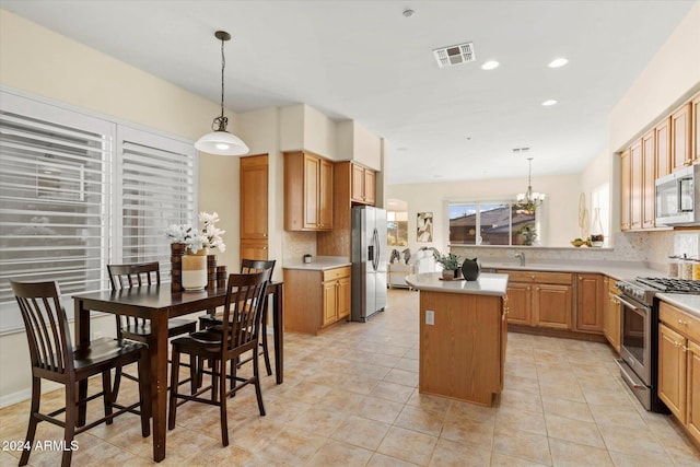 kitchen featuring pendant lighting, a center island, decorative backsplash, appliances with stainless steel finishes, and a notable chandelier