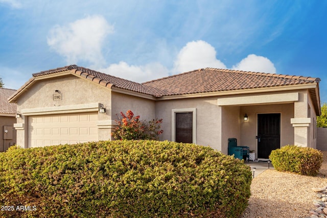 mediterranean / spanish house with an attached garage, a tile roof, and stucco siding