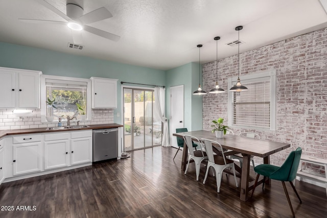 dining area with brick wall, visible vents, and dark wood-type flooring