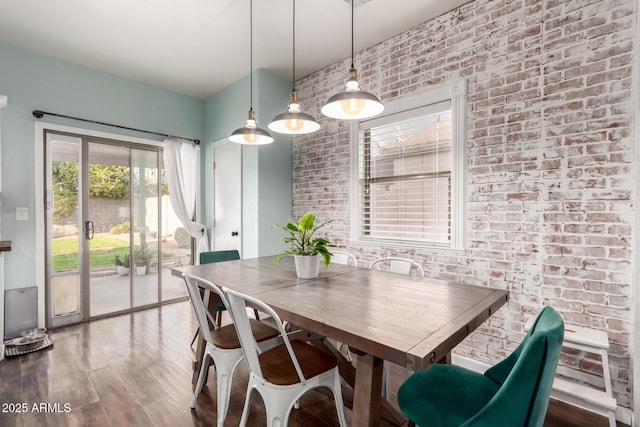 dining room featuring brick wall and wood finished floors