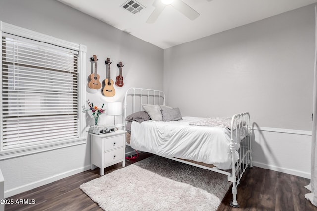 bedroom with a ceiling fan, visible vents, baseboards, and wood finished floors