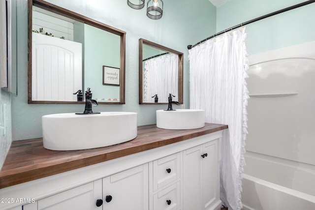 bathroom featuring double vanity, shower / bath combination with curtain, and a sink