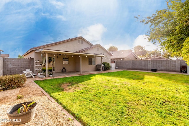 rear view of property with stucco siding, a fenced backyard, a lawn, and a patio