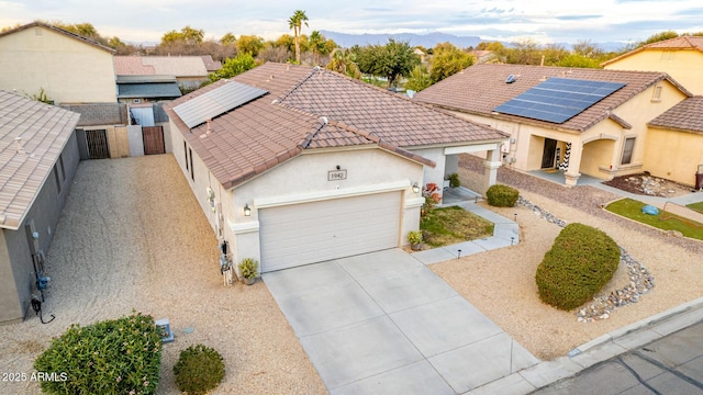 view of front of house featuring a garage, driveway, a tile roof, fence, and stucco siding