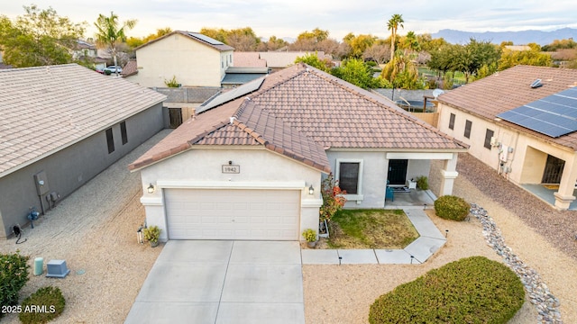 view of front of house with central air condition unit, stucco siding, concrete driveway, an attached garage, and a tiled roof