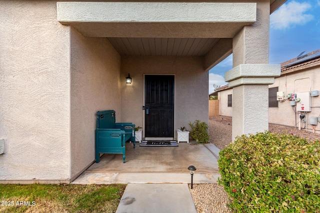 view of exterior entry with a patio and stucco siding