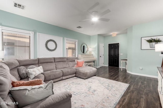 living room featuring dark wood-type flooring, a healthy amount of sunlight, visible vents, and baseboards