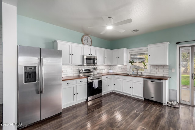 kitchen featuring backsplash, appliances with stainless steel finishes, wooden counters, and a sink