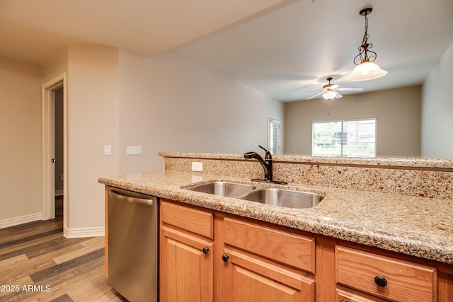 kitchen featuring sink, light stone counters, light hardwood / wood-style floors, decorative light fixtures, and stainless steel dishwasher