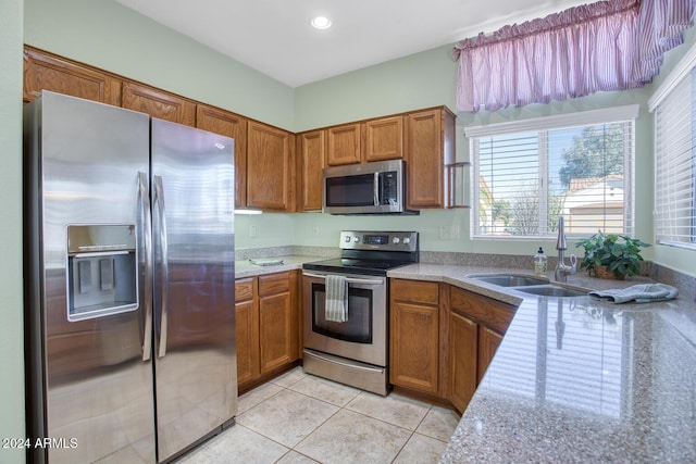 kitchen featuring light tile patterned flooring, sink, light stone countertops, and stainless steel appliances