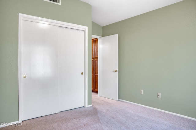 unfurnished bedroom featuring light carpet, vaulted ceiling, and a closet