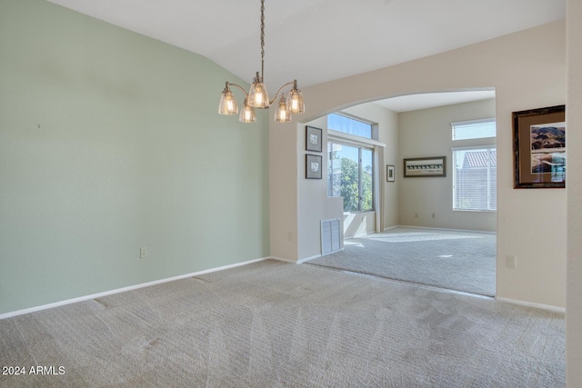 empty room with light colored carpet, vaulted ceiling, and a notable chandelier