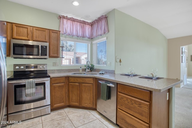 kitchen with sink, vaulted ceiling, light tile patterned floors, appliances with stainless steel finishes, and kitchen peninsula