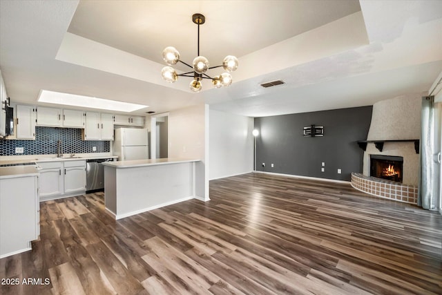 kitchen with white cabinetry, dark hardwood / wood-style flooring, white fridge, stainless steel dishwasher, and a raised ceiling