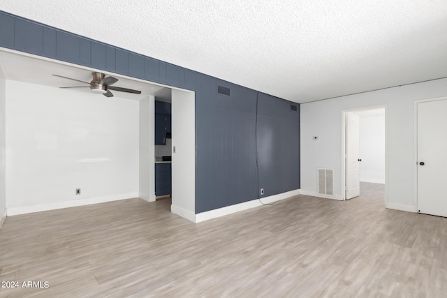 empty room with a textured ceiling, ceiling fan, and light wood-type flooring