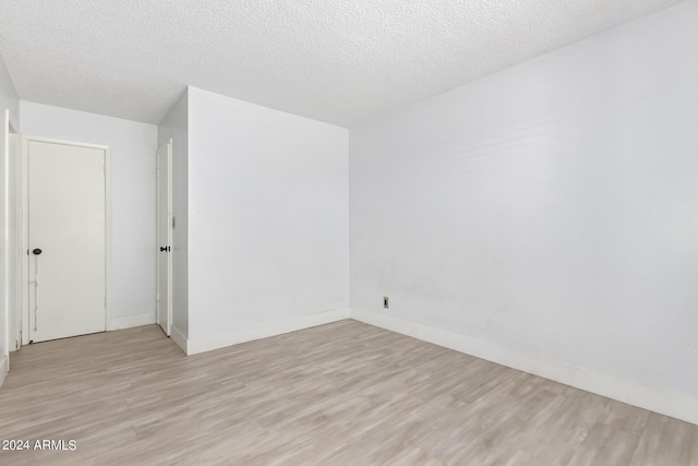 unfurnished room with a textured ceiling and light hardwood / wood-style flooring