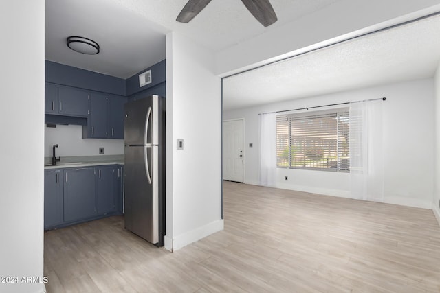 kitchen featuring light wood-type flooring, sink, blue cabinets, and stainless steel refrigerator