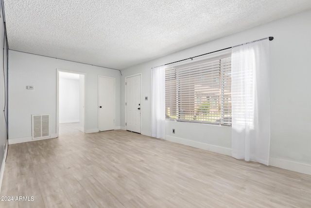 spare room with a textured ceiling and light wood-type flooring