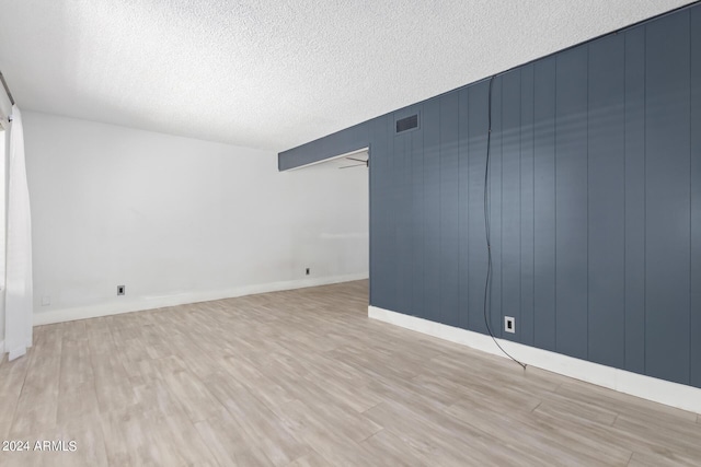 unfurnished room featuring a textured ceiling and light hardwood / wood-style flooring