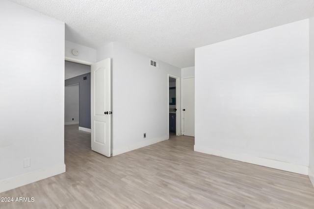 unfurnished room featuring a textured ceiling and light hardwood / wood-style floors