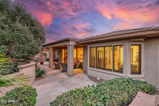 back house at dusk featuring outdoor lounge area and a patio