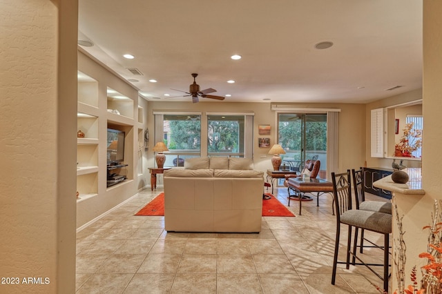 tiled living room with built in features and ceiling fan